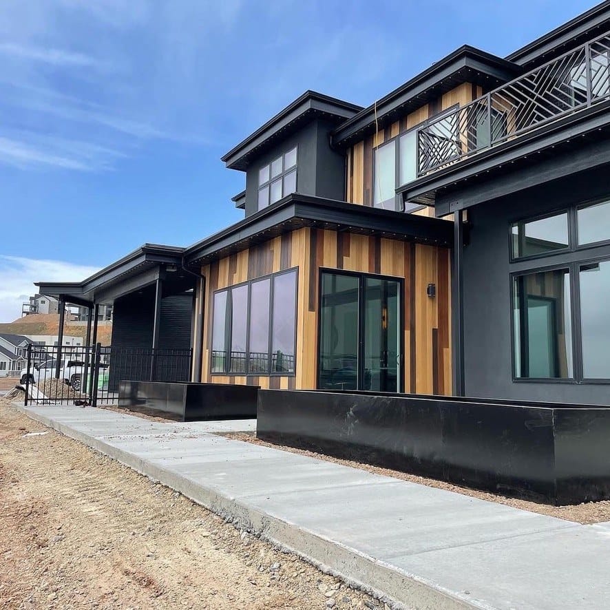 Finished black steel planter boxes running along the facade of a dark stucco and cedar home